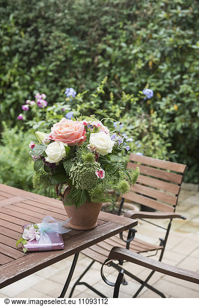 Gift with bouquet of flowers on table in garden  Munich  Bavaria  Germany