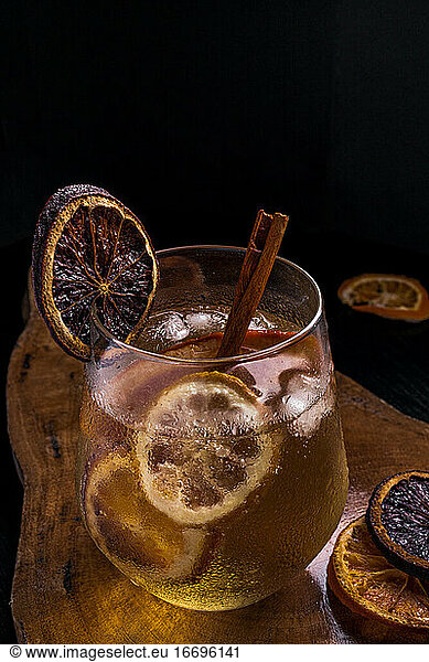 Gin tonic cocktail with cinnamon and lemon on a wooden table