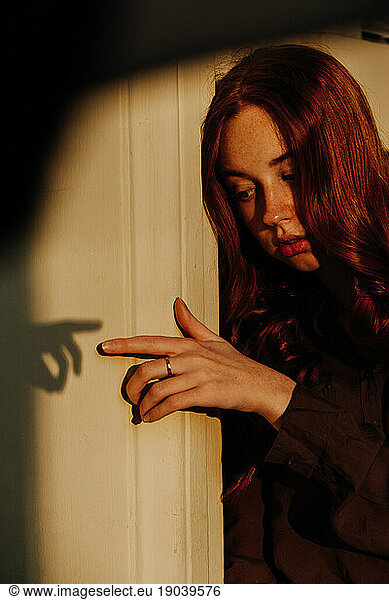 Ginger Girl with Freckles at Sunset Is Touching her Shadow