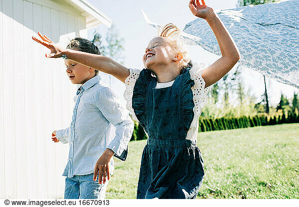 girl and boy running through the washing on the line with great joy