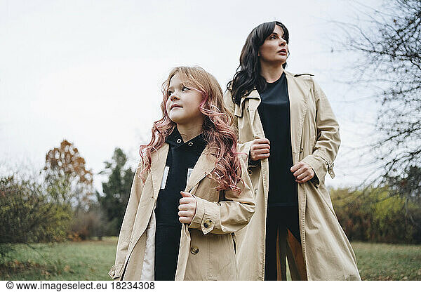 Girl and mother wearing trench coat at park