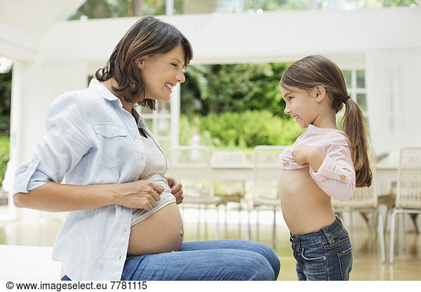 Girl and pregnant mother comparing bellies