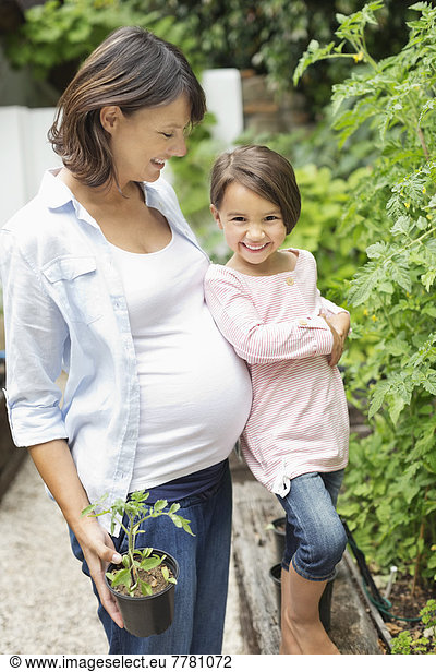 Girl and pregnant mother gardening together