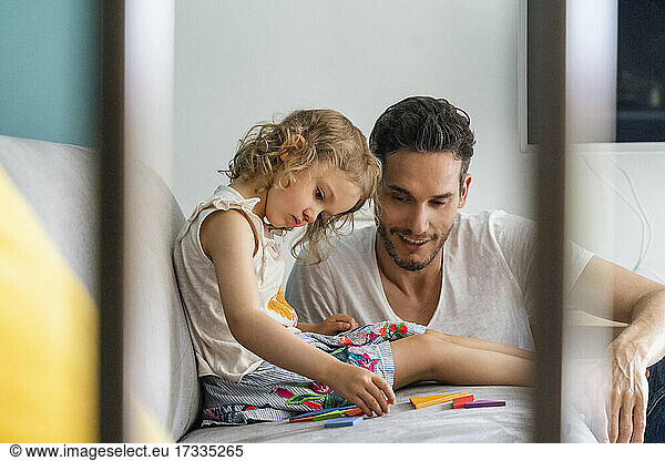 Girl arranging puzzle while sitting with father at home