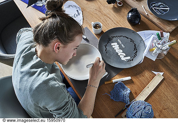 Girl at home painting bowl with porcelain paint