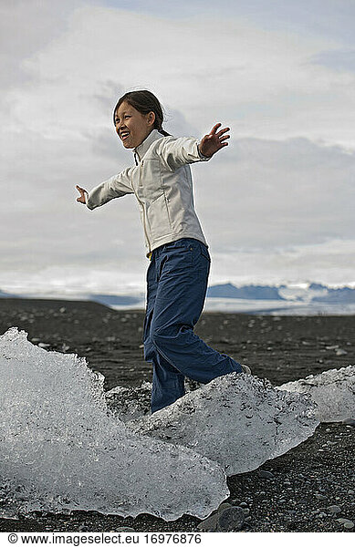 girl balancing on stranded iceberg at glacier lagoon in Iceland