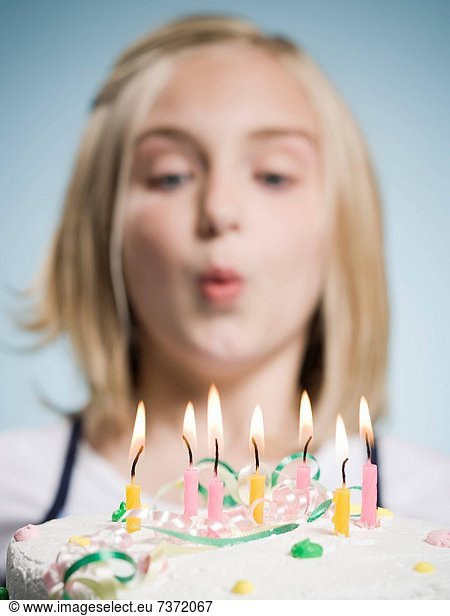 Girl blowing out candles on a birthday cake