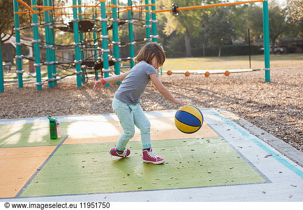 Girl bouncing basketball in playground
