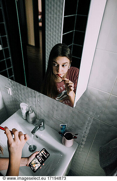 Girl brushing her teeth and holding her phone