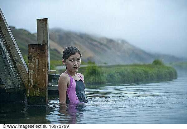 girl carefully taking a bath at geothermal hot spring in Iceland