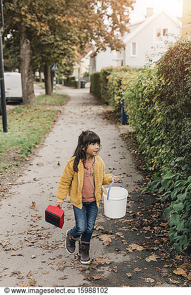 Girl carrying bucket while walking on footpath