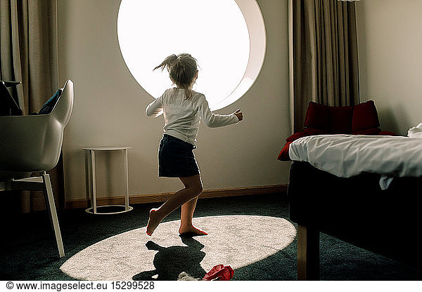 Girl dancing against window in hotel room