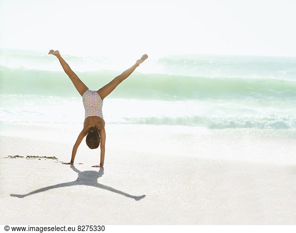 Girl doing cartwheel on beach