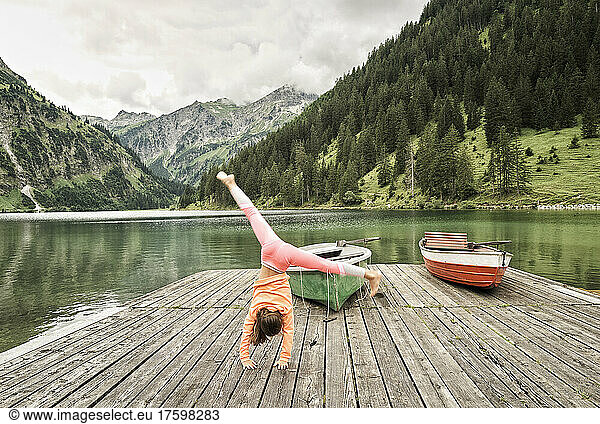 Girl doing cartwheel on jetty by lake