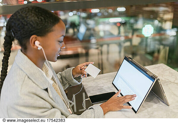 Girl doing online payment with credit card using touch screen laptop at cafe