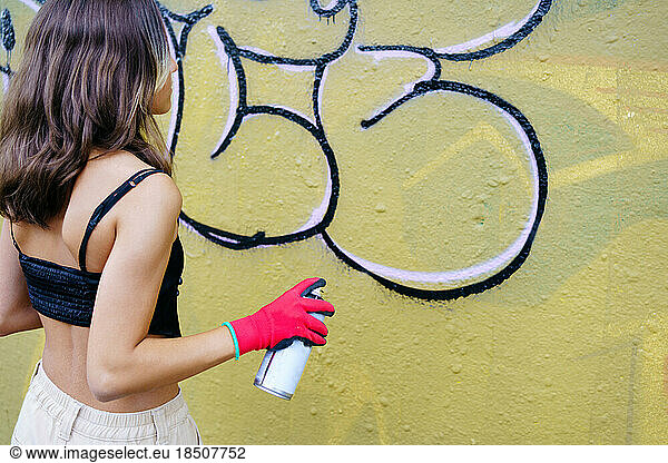 Girl drawing graffiti on the city wall