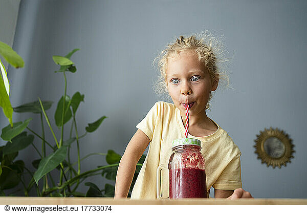 Girl drinking healthy fruit smoothie through straw