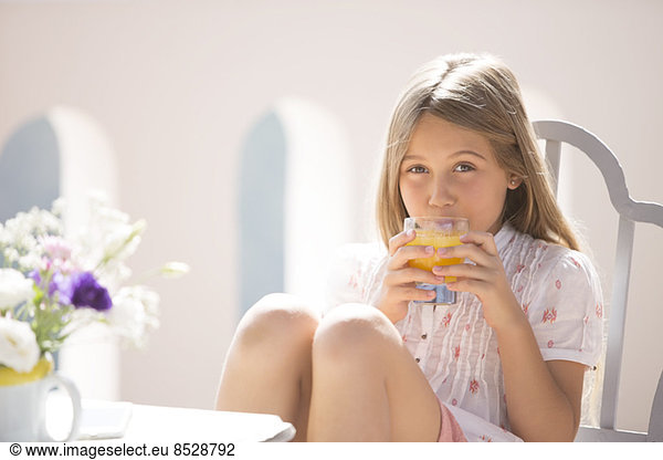 Girl drinking juice at table outdoors