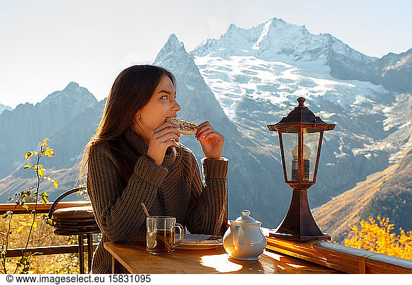 Girl drinks tea and eats in the mountains