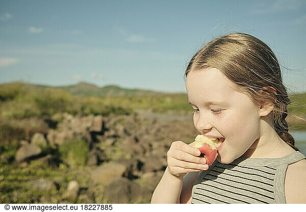 Girl eating apple in countryside
