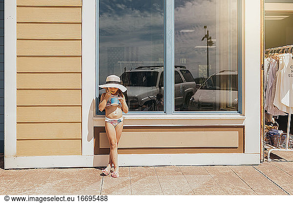 Girl Eating Ice Cream in Front of Beachfront Cafe
