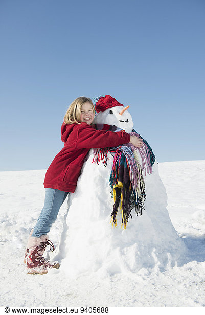 Girl embracing snowman  smiling
