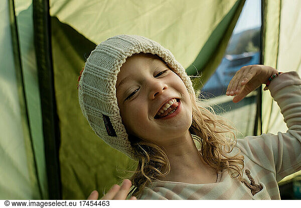 girl feeling happy in a tent whilst camping with family on a campsite