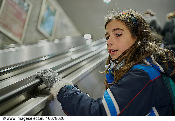 girl goes up the subway escalator looking back