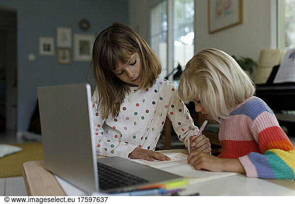 Girl helping sister doing homework at home