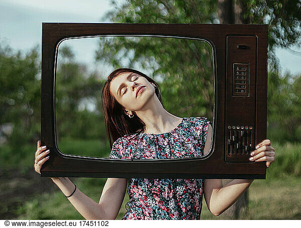Girl hold vintage tv frame outdoors