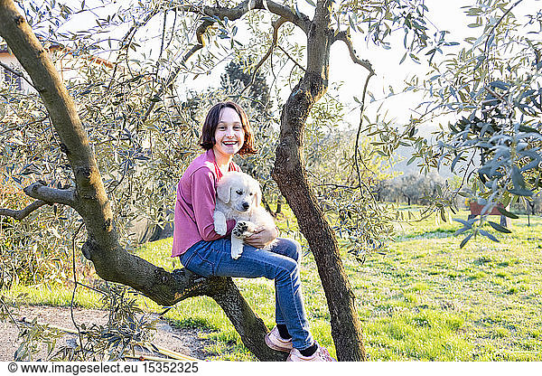 Girl holding a cute golden retriever puppy on tree in orchard  portrait  Scandicci  Tuscany  Italy