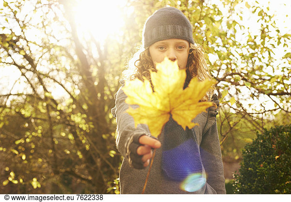 Girl holding autumn leaf outdoors