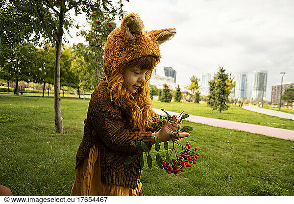 Girl holding berry fruit twig in public park