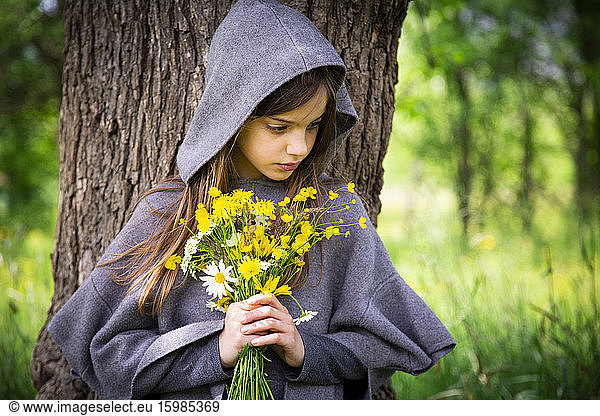 Girl holding bunch of yellow wildflowers