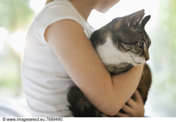 Girl holding cat indoors