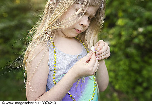 Girl holding flower while standing at backyard