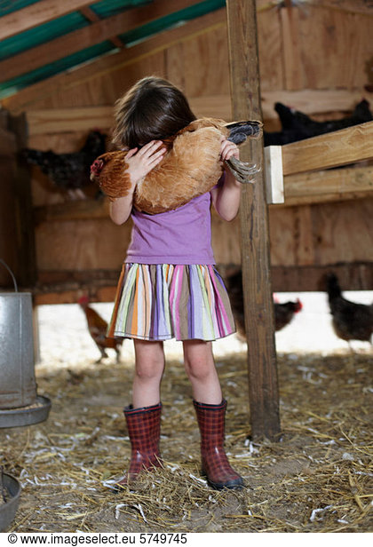 Girl holding hen in hen house
