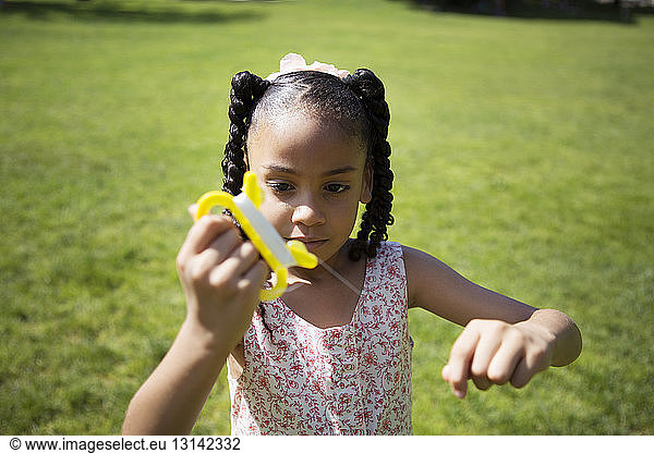 Girl holding kite string on grassy field