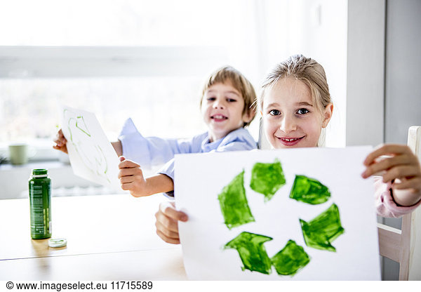 Girl holding paper with painted recycling symbol