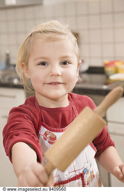 Girl holding rolling pin  smiling  portrait