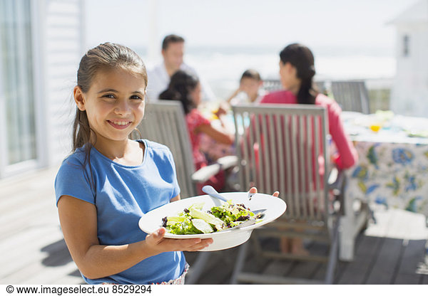 Girl holding salad on sunny patio