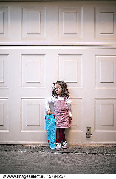 Girl holding skateboard at a garage