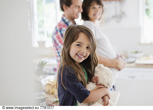 Girl holding teddy bear in kitchen
