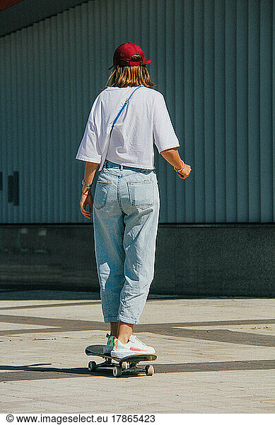 girl in a white t-shirt and jeans rides a skateboard