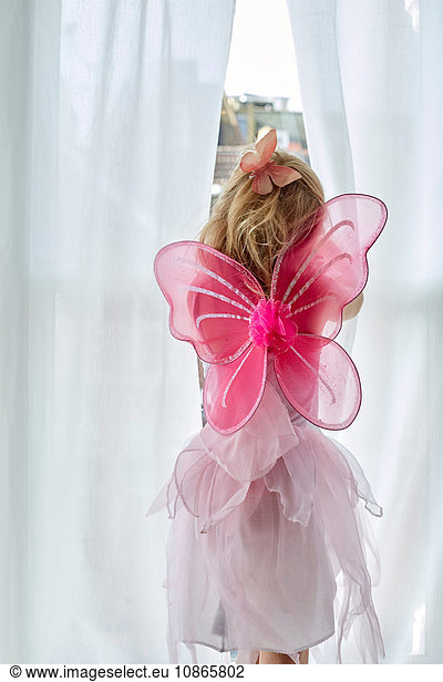 Girl in fairy costume peeking through curtain