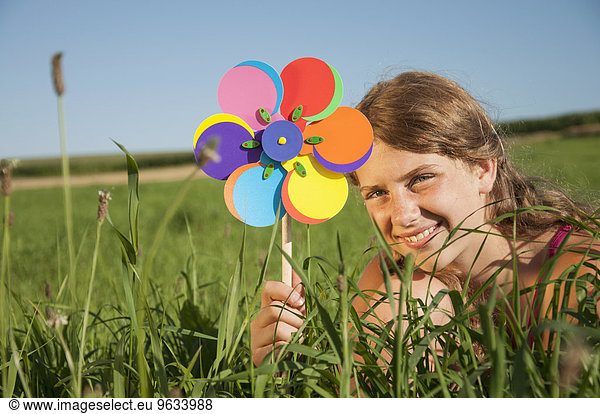 Girl (12-13) in field holding wind wheel  smiling  portrait