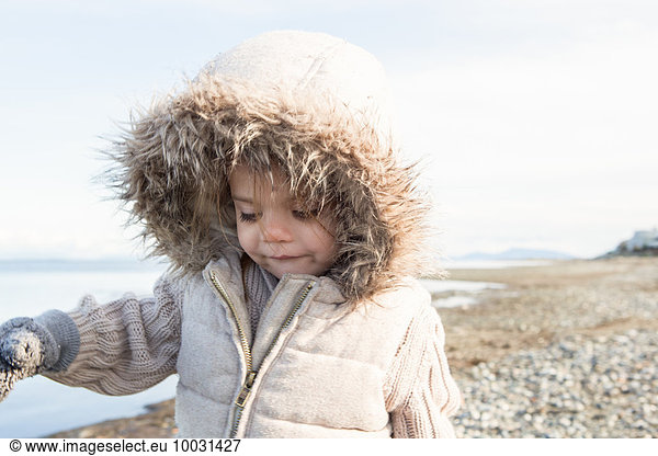 Girl in fur hood jacket walking on beach