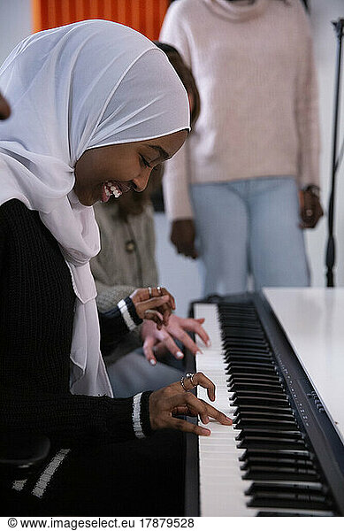 Girl in hijab playing piano in recording studio
