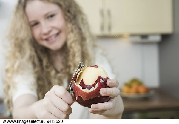 Girl in kitchen peeling apple