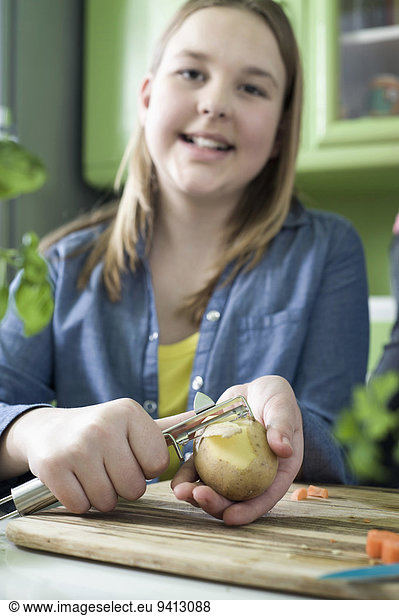 Girl in kitchen peeling vegetabels